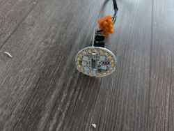 Round LED board with wires on a wooden floor.