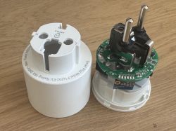 Disassembled smart electrical plug on a wooden surface.
