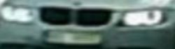 Rozmyte zbliżenie przodu auta BMW z widocznym grillem i reflektorami