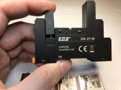 Adapter przekaźnika F&amp;F GN-2P-M trzymany w dłoni, z opisanymi parametrami.