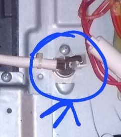 Zdjęcie elementu urządzenia, zaznaczonego niebieskim kółkiem, przedstawiające wyłącznik termiczny.