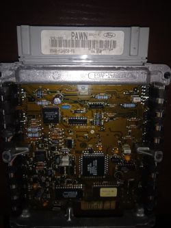 Otwarty sterownik ECU Ford EEC‑IV z widoczną płytką i etykietą „PAWN” oraz numerami części