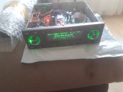 Open car radio housing with green-lit display and visible internal electronics