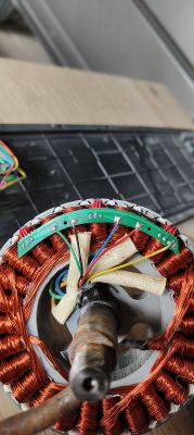 Stator silnika elektrycznego z nawiniętym miedzianym drutem i kolorowymi przewodami.