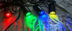 Four LED spotlights emitting light in red, green, blue, and yellow colors.