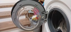Otworzone drzwi pralki Beko z widoczną uszkodzoną klamką.