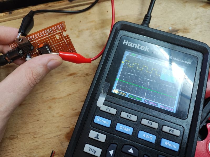 Oscilloscope with PWM Signal and Circuit Prototype Hantek oscilloscope displaying a PWM signal next to a circuit prototype on a board.