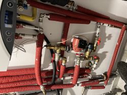 Pompa Grundfos w instalacji grzewczej z rurami w czerwonej izolacji termicznej