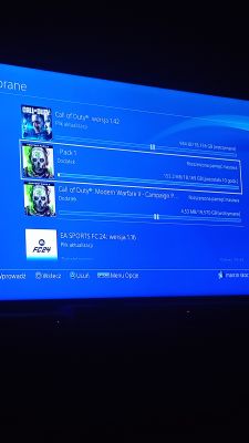 Ekran pobierania na PS4 Slim z widocznymi wolnymi transferami aktualizacji gier.