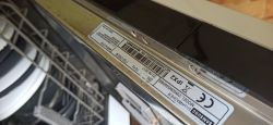 Tabliczka znamionowa zmywarki Samsung DW60M5060BB umieszczona na krawędzi drzwi.