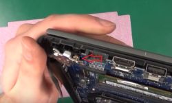 Zbliżenie wnętrza laptopa Dell Vostro 5568, pokazujące uszkodzoną złotą tulejkę przy zawiasie.