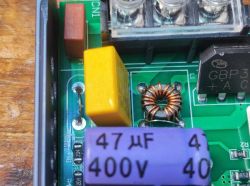Close-up of a power supply interior with toroidal choke, capacitors, and bridge rectifier