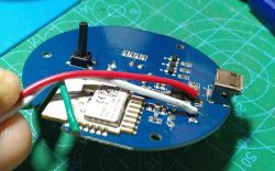 Close-up of a blue PCB with connected wires, a microcontroller, and a USB port.