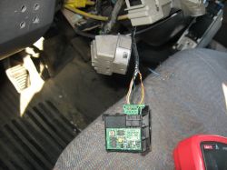 Wnętrze samochodu z widoczną usuniętą kostką elektryczną i przewodami na fotelu.