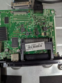 Close-up of a circuit board with chips, connectors, and a barcode label on a large black socket