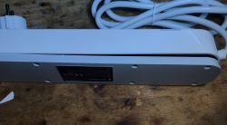 Gembird TSL-PS-F4U-01-W power strip upside down with feet removed and lower cover slightly opened.