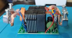 Close-up of an electronic module with visible heat sinks, wires, and copper components.