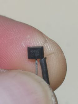 Zdjęcie przedstawia zbliżenie małego czujnika Halla z oznaczeniem D49E 211H trzymanego w palcach.