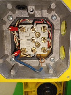 Wnętrze skrzynki elektrycznej z widocznymi przewodami i zaciskami.