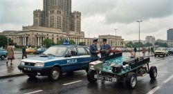 Police officers near patrol car and large Arduino-shaped vehicle in front of the Palace of Culture