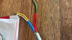 Zbliżenie na przewody elektryczne z koszulkami termokurczliwymi na tle drewnianego blatu