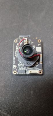 Kamera modułowa z soczewką i okablowaniem na ciemnym tle.