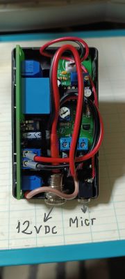 Układ elektroniczny w czarnej obudowie z widocznymi przewodami i komponentami podłączonymi do zasilania 12V DC i mikrofonu.