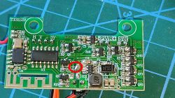 Zielona płytka PCB z elementami SMD; widoczne pola lutownicze H, V, −, 3V i czerwone kółko przy „+”.