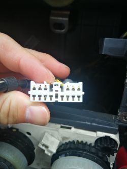 Osoba trzyma białą wtyczkę elektryczną w samochodzie.