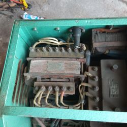 Wnętrze starego agregatu z widocznymi przewodami, zaciskami i elementami elektrycznymi.