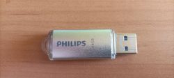 Pendrive Philips 64 GB z metalową obudową leży poziomo na drewnianym blacie