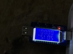 Backlit USB meter displaying 5.15 V voltage and 0.00 A current, connected to a USB port.