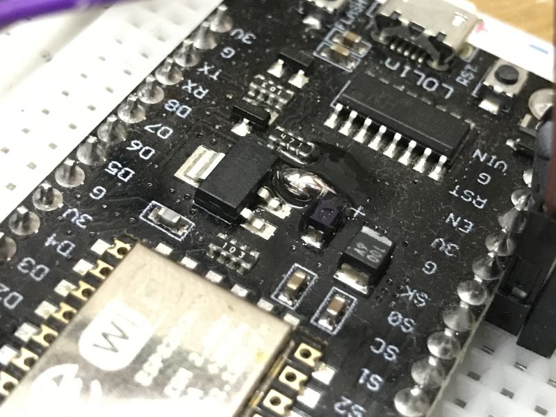 Zbliżenie na płytkę NodeMCU z widocznymi pinami i lutowanymi przewodami