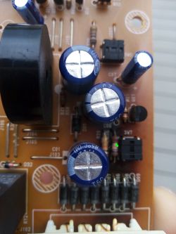 Zbliżenie płytki PCB z kondensatorami; zielona kropka wskazuje przypalony rezystor