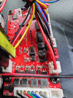 Czerwona płytka PCB z wieloma przewodami, rezystorami i złączami