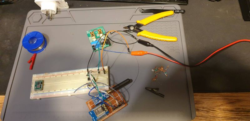 Electronics prototyping setup with ESP8266 board, radio modules, breadboard wiring on an ESD mat