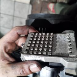 Brudna ręka trzymająca metalowy element o kwadratowych wypustkach.