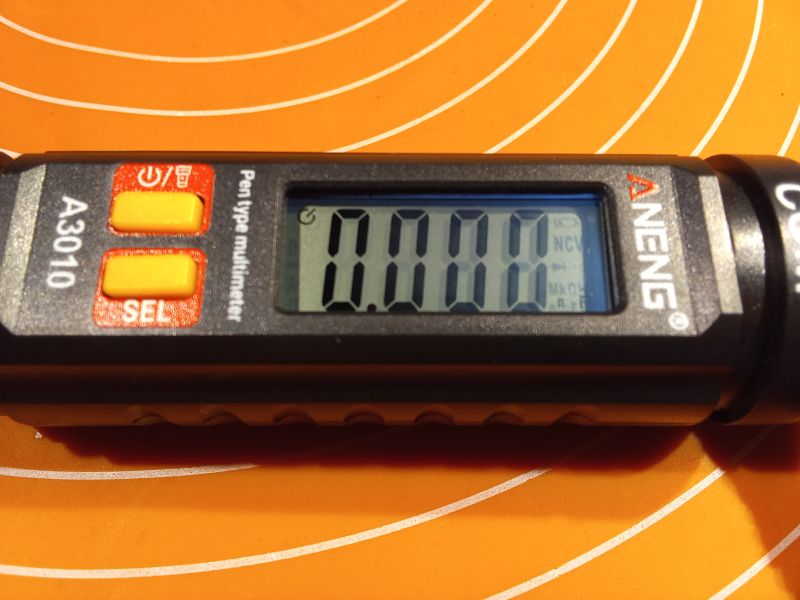 Miernik uniwersalny ANENG A3010 z wyświetlaczem i przyciskami na tle pomarańczowej powierzchni.