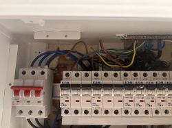 Widok wnętrza rozdzielnicy elektrycznej z wyłącznikami nadprądowymi i kablami.