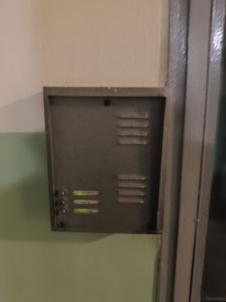 Metalowy panel domofonowy z trzema przyciskami i opisanymi etykietami nazwisk