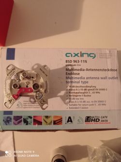 Gniazdo antenowe Axing BSD 963-11N na tle pudełka.