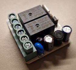 Close-up of a PCB with a screw terminal block, two relays, and capacitors