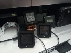 Several electronic devices on a desk, including three digital thermometers.