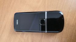 Czarny telefon Nokia z wysuwanym mechanizmem leży na drewnianej powierzchni, widok z góry.