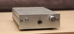 Silver headphone amplifier with volume knob and headphone output.
