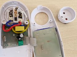 Wnętrze rozebranego urządzenia elektrycznego z widocznymi przewodami i komponentami.
