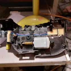 Otwarty siłownik zamka z widocznym silniczkiem i mikroprzełącznikiem.