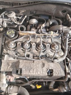 Widok silnika samochodowego z góry, z widocznymi przewodami i elementami mechanicznymi.