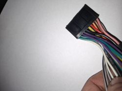 Czarna wtyczka instalacji radia samochodowego z wielokolorowymi przewodami na białym tle