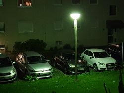 Widok nocny na parking z samochodami oświetlony migającą latarnią